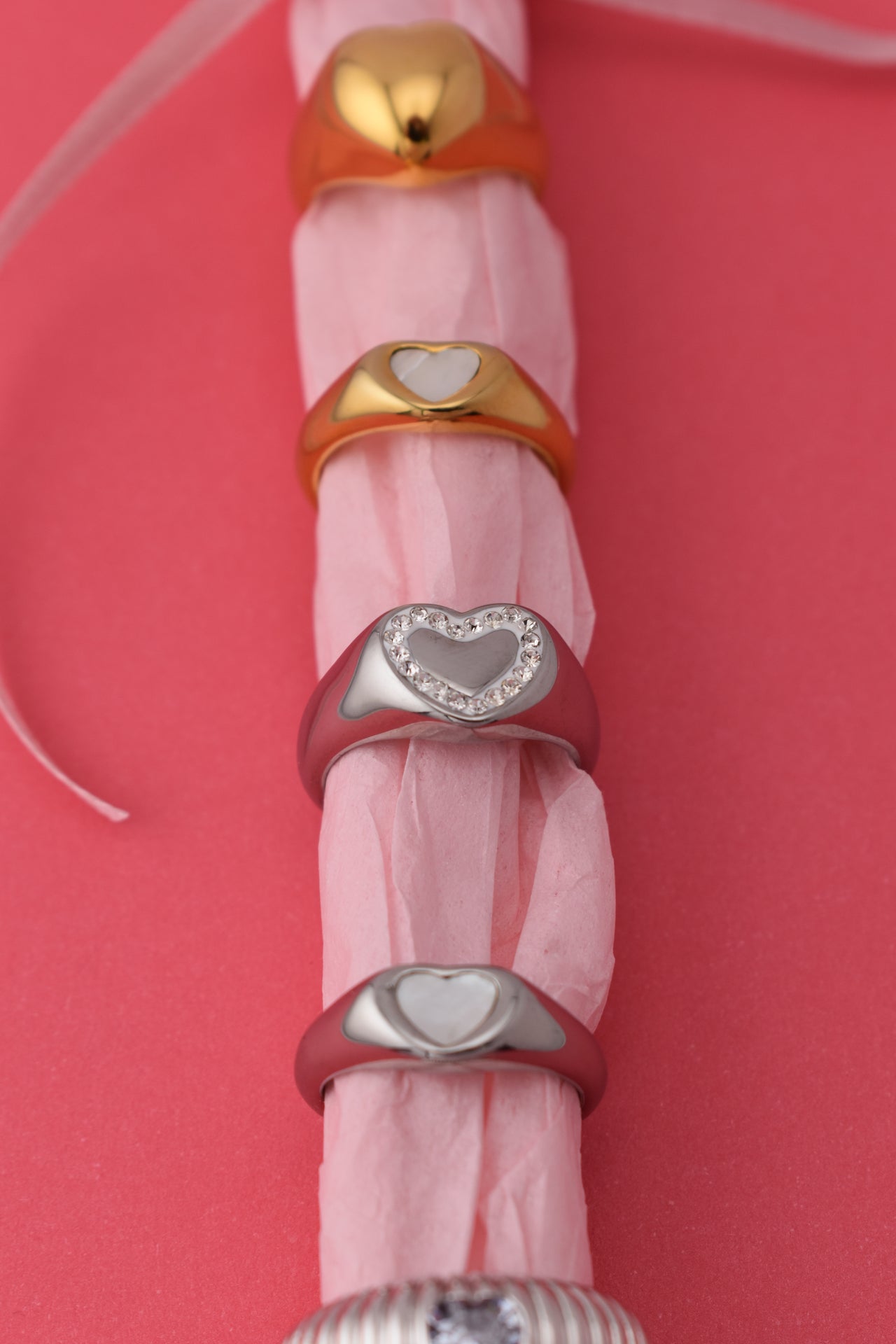 A silver-colored signet heart ring with clear crystal stones set in a white inlay, available in two US ring sizes.