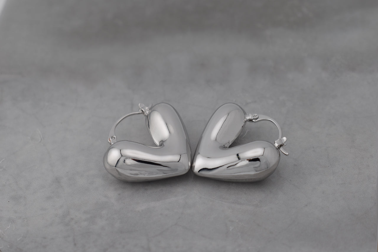 Puffy Silver Heart Earrings with latch back closure against white background
